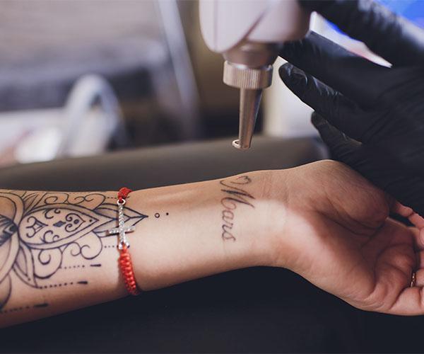 A person with tattoos on their arm and wrist.