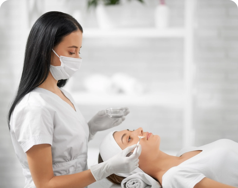 A woman is getting her face cleaned by a nurse.